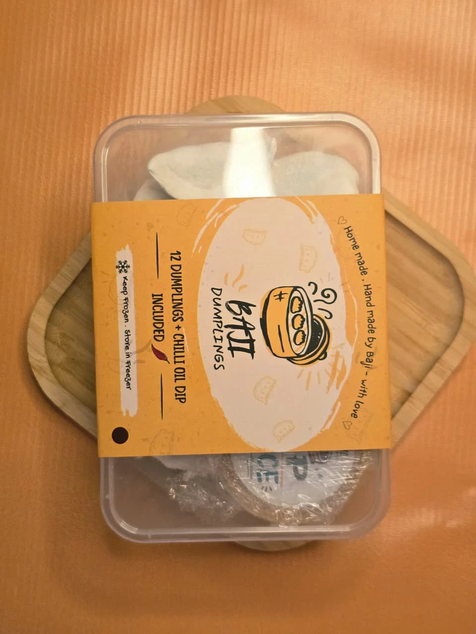 Baji Dumplings 12-piece box with chilli oil dip, on a wooden board