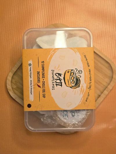 Baji Dumplings 12-piece box with chilli oil dip, on a wooden board