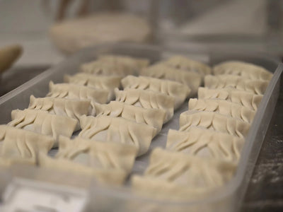 Close-up of hand-pleated dumplings on a tray