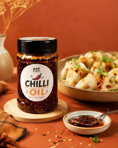 Baji's Chilli Oil beside a plate of dumplings and a dipping bowl